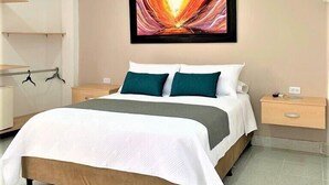 Habitació d'hotel amb un llit, una petita taula de nit, una obra d'art penjada a la paret i un armari.