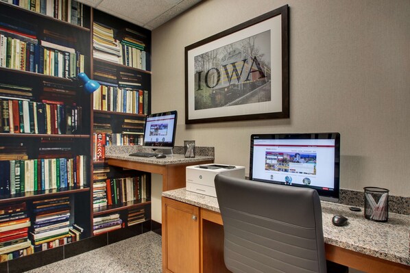 A library with bookshelves, two desktop computers, a framed picture of Iowa, and a desk with a chair.