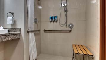 Un espace douche équipé d’un banc, de barres d’appui et d’un porte-serviettes.