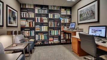 Una biblioteca con estanterías, un escritorio con una computadora, una silla y una lámpara.