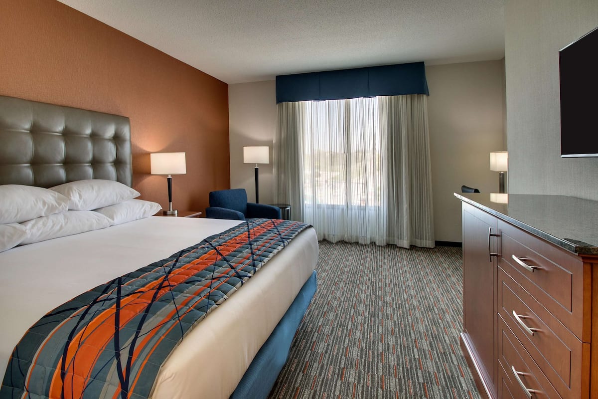 Une chambre d’hôtel avec un grand lit, un bureau, une chaise, une télévision et une armoire.