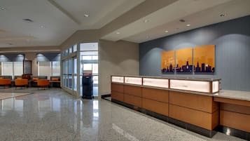 A modern lobby with a reception desk, seating area, and large windows.