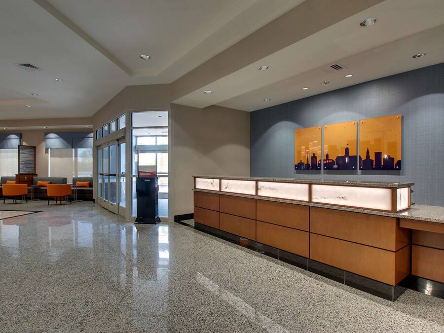 A modern lobby with a reception desk, seating area, and large windows.