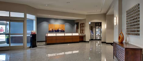 A spacious lobby with a polished granite floor, a reception desk, and a large wall-mounted display.