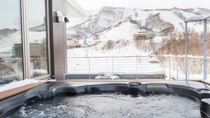 A hot tub on a balcony with a snowy mountain view. - Niseko Central Condominiums (Kutchan)