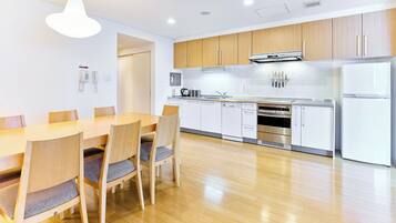 A modern kitchen with wooden cabinets, a stainless steel refrigerator, and a dining area with a wooden table and chairs.