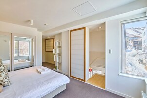 Una habitación de hotel moderna con una cama grande, un vestidor y vistas a un paisaje nevado.