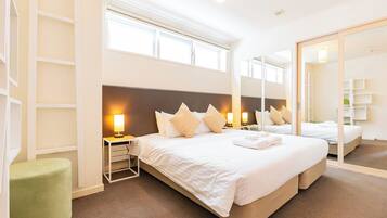 A hotel room with a large bed, bedside lamps, a green ottoman, and a mirror reflecting the room.