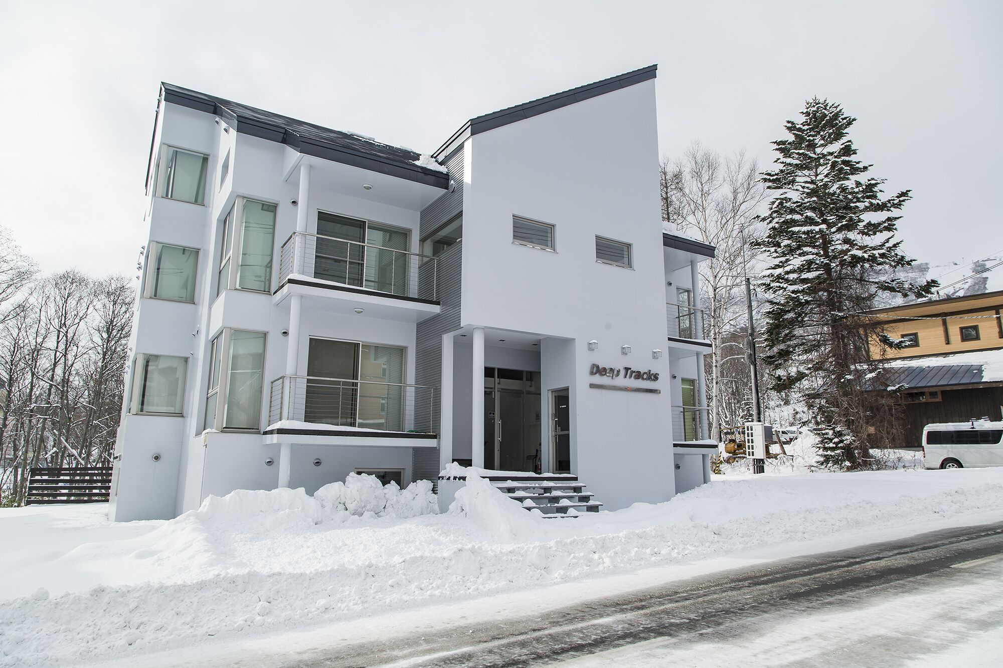 Un edificio moderno a più piani con tetto piatto e ampie finestre, con la scritta 'Deep Tracks'.