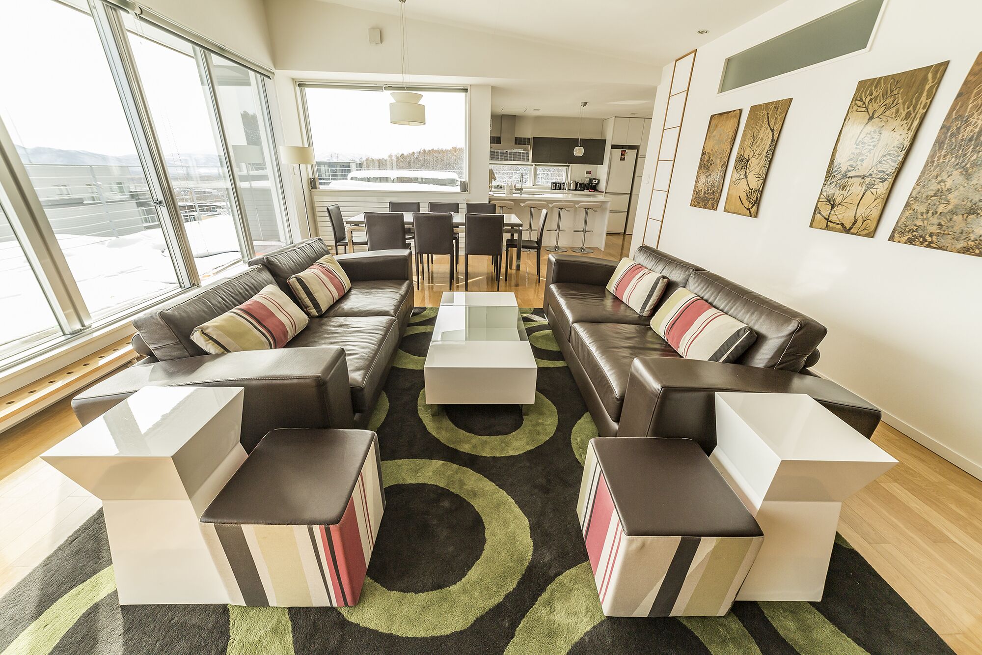 A modern living room with a sofa set, coffee tables, and a view of the city through large windows.