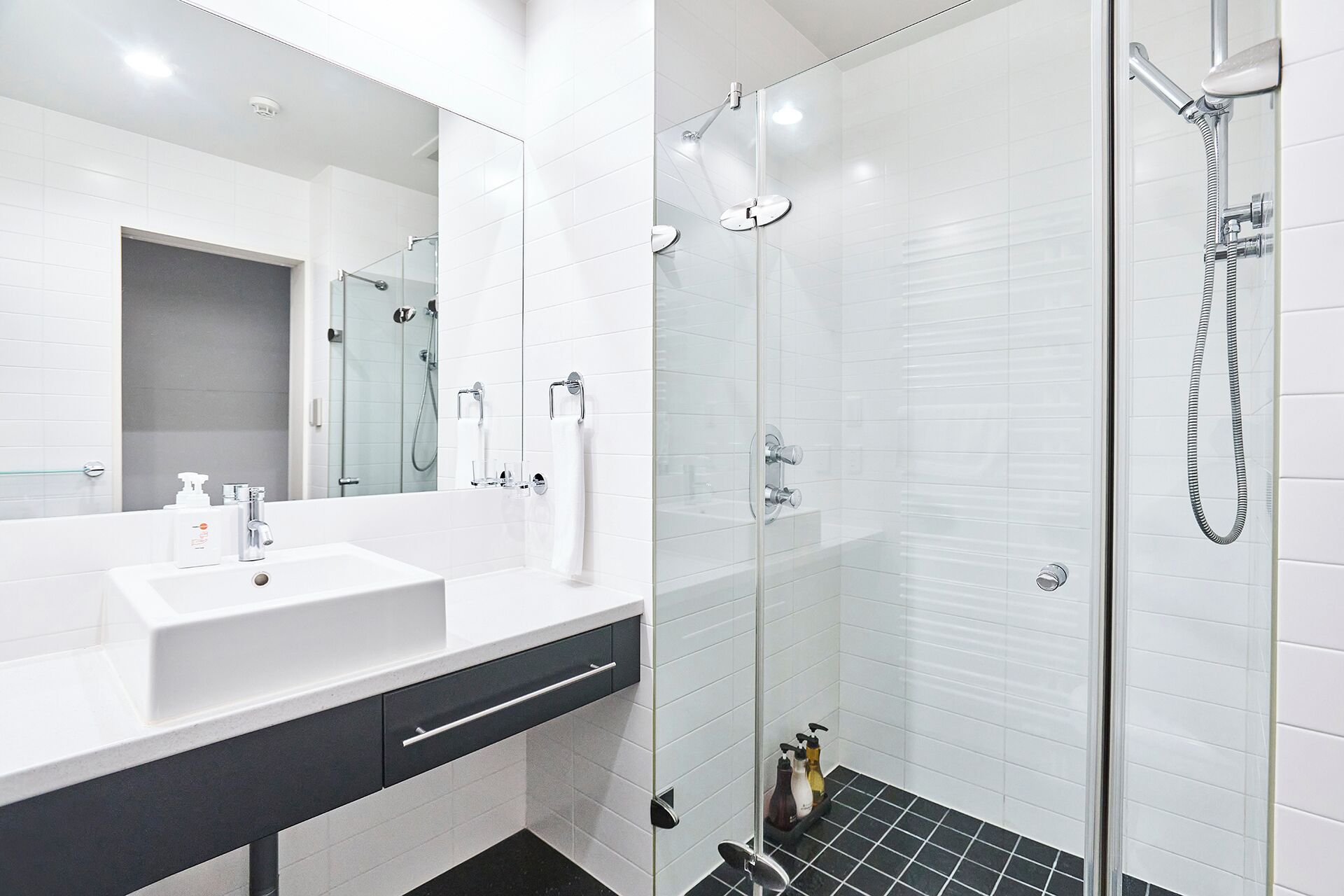 Un baño moderno con un lavamanos blanco, una cabina de ducha de vidrio y un espejo.