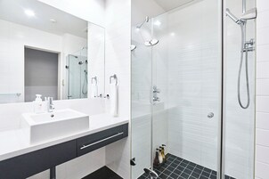 Un baño moderno con un lavamanos blanco, una cabina de ducha de vidrio y un espejo.