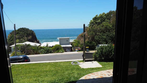 A view from a balcony overlooking a grassy area, a road, and the ocean. - WAVEBREAKER Scotts Head (Scotts Head)
