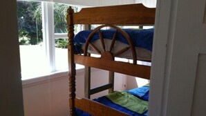 A bunk bed with a wooden frame and a wheel design on the top bunk. - The Little Cottage 3 minutes walk to beach. Beds for 5. (Henderson Bay)