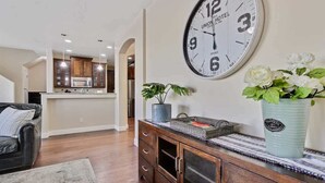 Une cuisine moderne avec des meubles en bois, une grande horloge murale et une plante en pot.