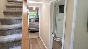 A staircase with wooden railings leading to a bedroom with a bed and a window.