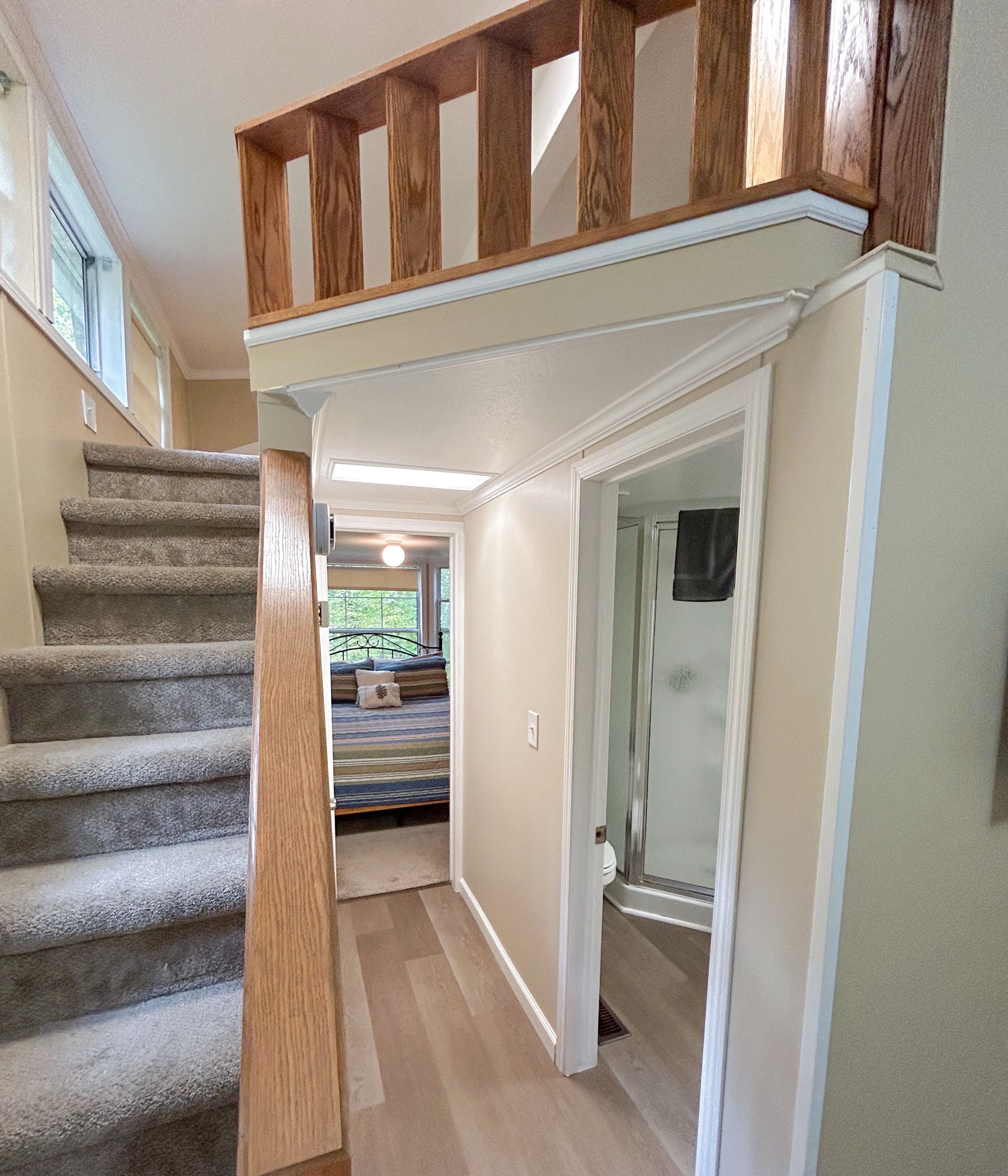 Un escalier avec des rampes en bois menant à une chambre à coucher qui contient un lit et une fenêtre.