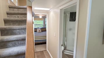 Un escalier avec des rampes en bois menant à une chambre à coucher qui contient un lit et une fenêtre.