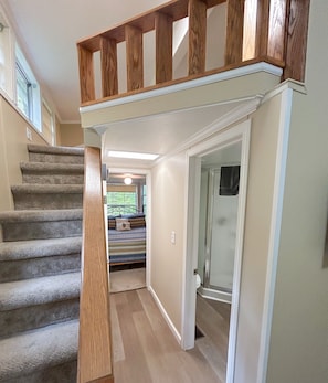 A staircase with wooden railings leading to a bedroom with a bed and a window.