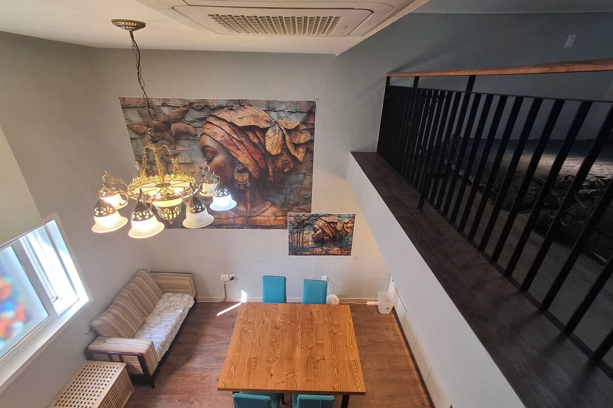 A dining area with a wooden table and chairs, a bench, and a large wall mural.