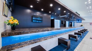 A modern reception area with a marble counter, a blue carpet, and a wall-mounted TV. - Toyoko Inn Nagoya Meieki Minami (Nagoya)