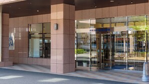 A modern building with a glass entrance, a signboard, and a tiled pavement. - Toyoko Inn Nagoya Meieki Minami (Nagoya)