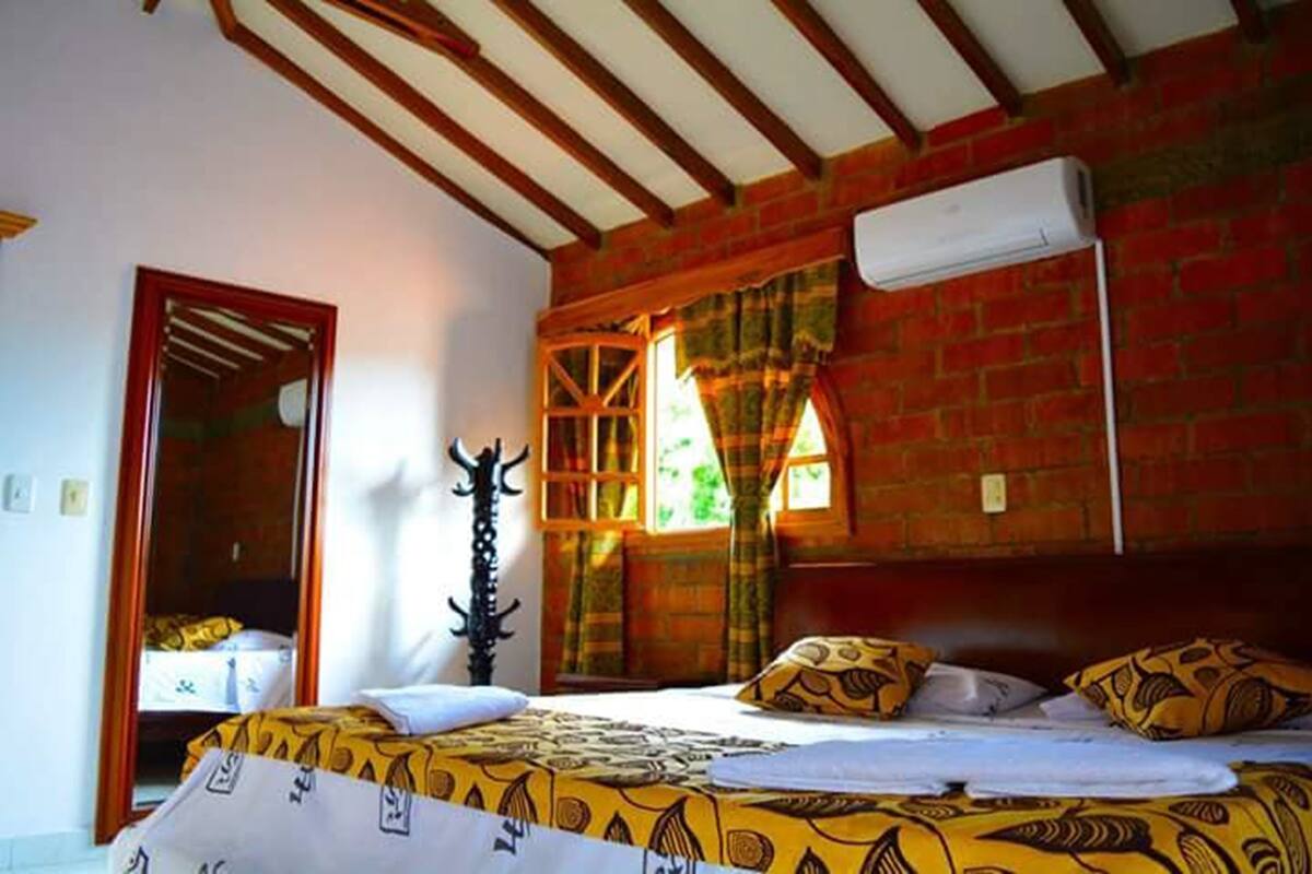 Ein Zimmer mit einem Bett, einem Vorhangfenster, einer Tür und einer Wand-Klimaanlage.