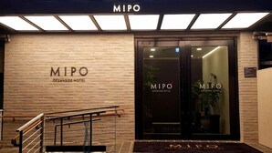 The entrance of MIPO Oceanside Hotel with a brick facade, glass doors, and a metal staircase leading up. - Mipo Oceanside Hotel (Busan)
