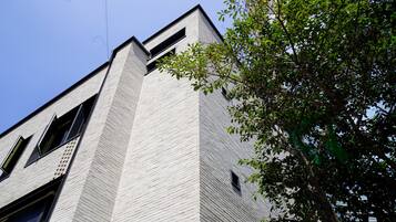 A modern building with a prominent corner, large windows, and a tree in the foreground.