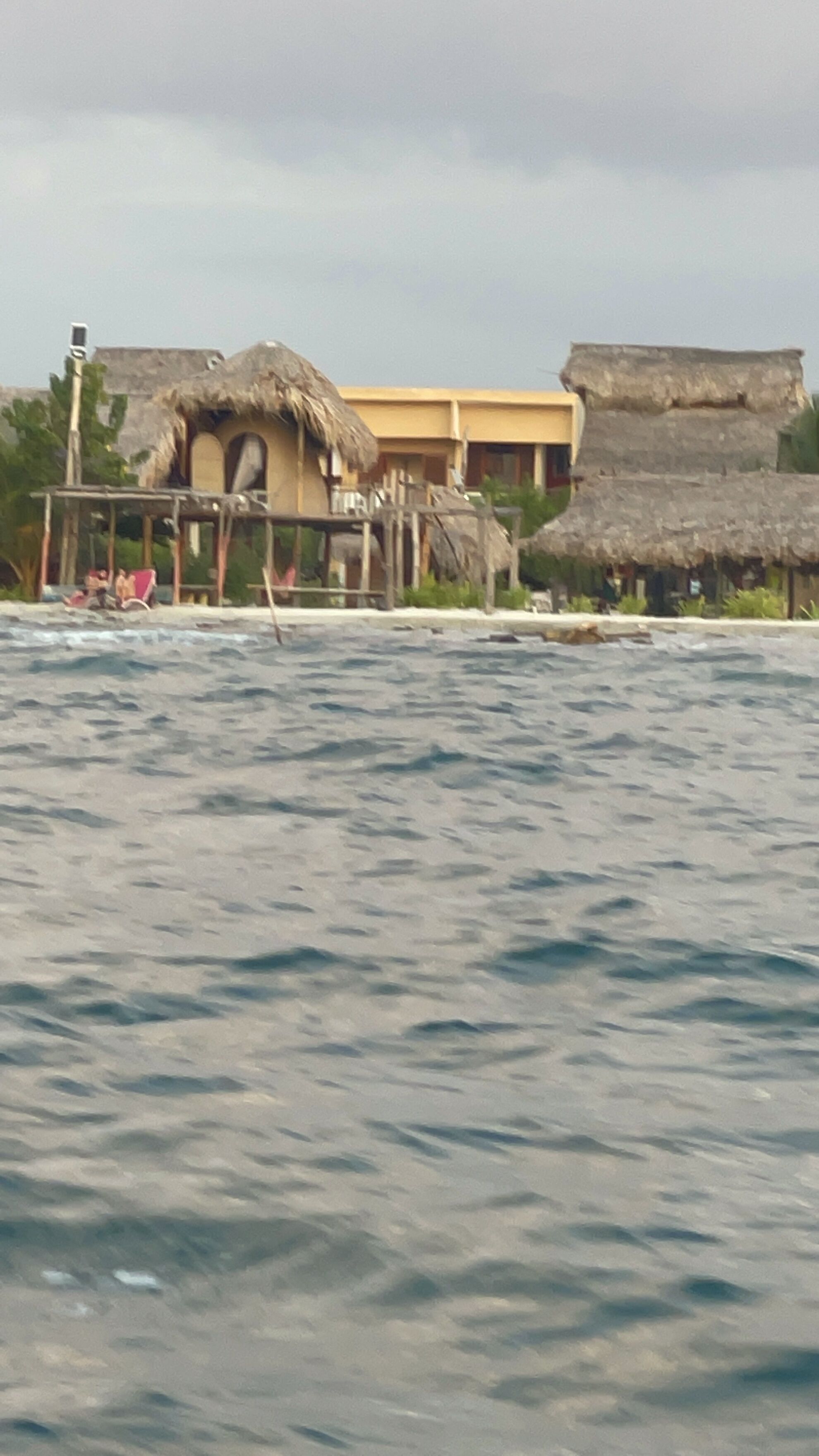 A beachside building with a thatched roof, a visible swimming area, and a view of the sea.