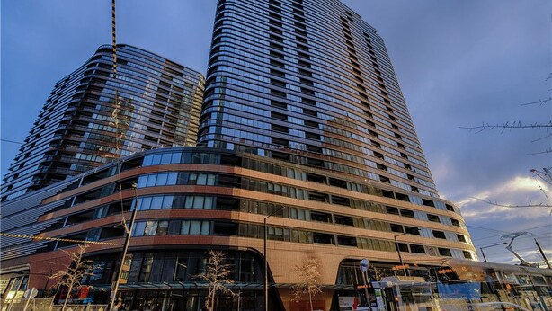 A modern high-rise building with a curved facade and multiple balconies. - APC on Collins (Docklands)