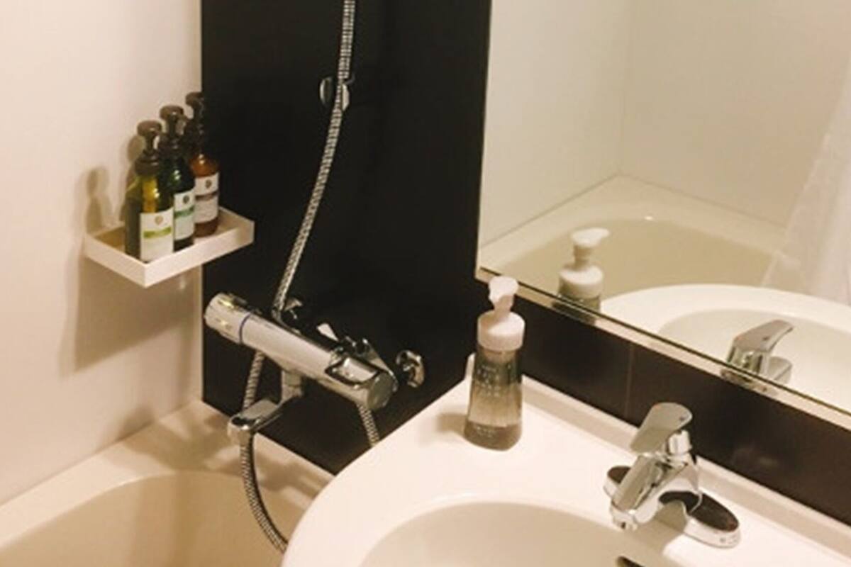 Ein Badezimmer mit weißem Waschbecken, einem Spiegel, einer Dusche und einem Ablagefach für Toilettenartikel.
