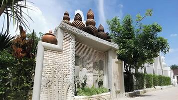 Un edificio con fachada de ladrillo y detalles decorativos, rodeado de follaje y árboles.