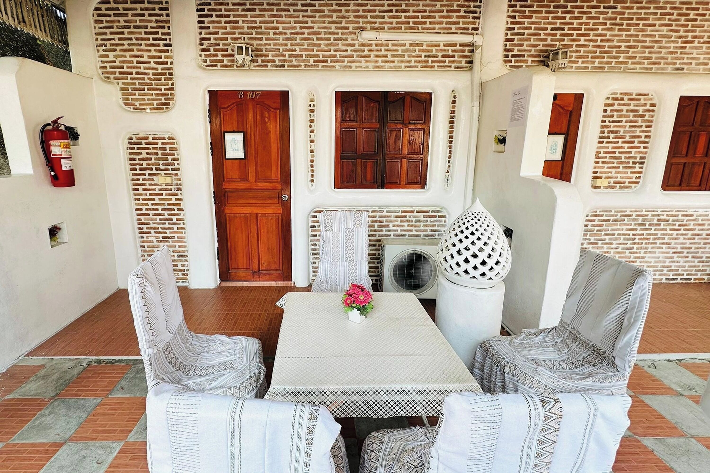 A patio with a table and two chairs, a wooden door, and a fire extinguisher.