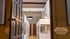 An interior hallway with arched doorways leading to a room with a bed and a desk. - Vloft Backpackers Hostel (Ipoh)