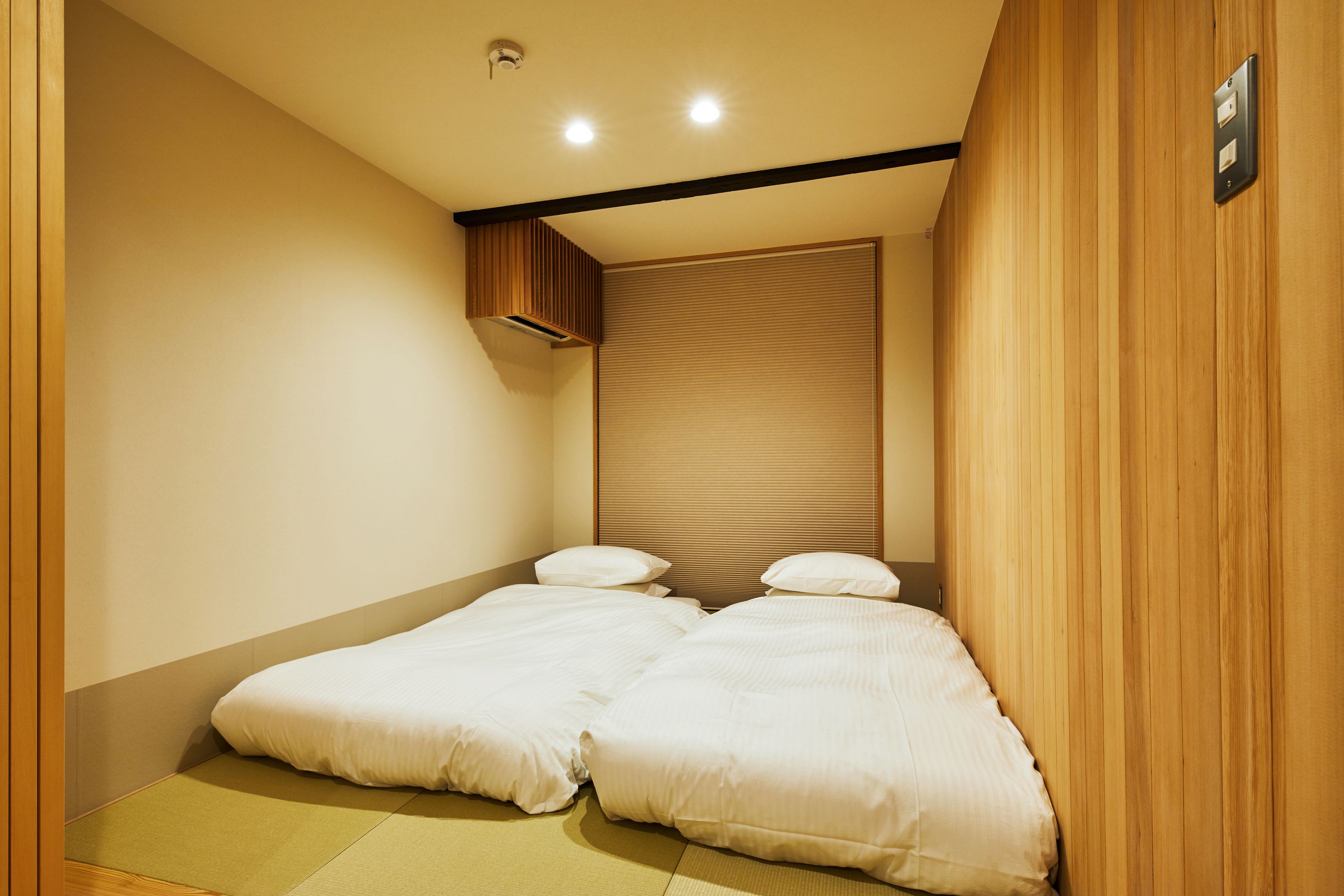 Une chambre avec deux lits, un mur recouvert de panneaux en bois et un luminaire au plafond.