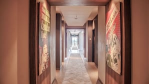 Um corredor de hotel com painéis de madeira, piso coberto de carpete e cartazes nas paredes.