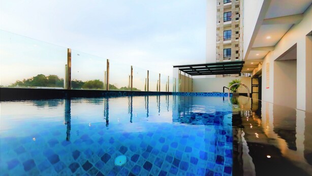Piscina com água azul cristalina, rodeada por um edifício moderno com fachada de vidro.
