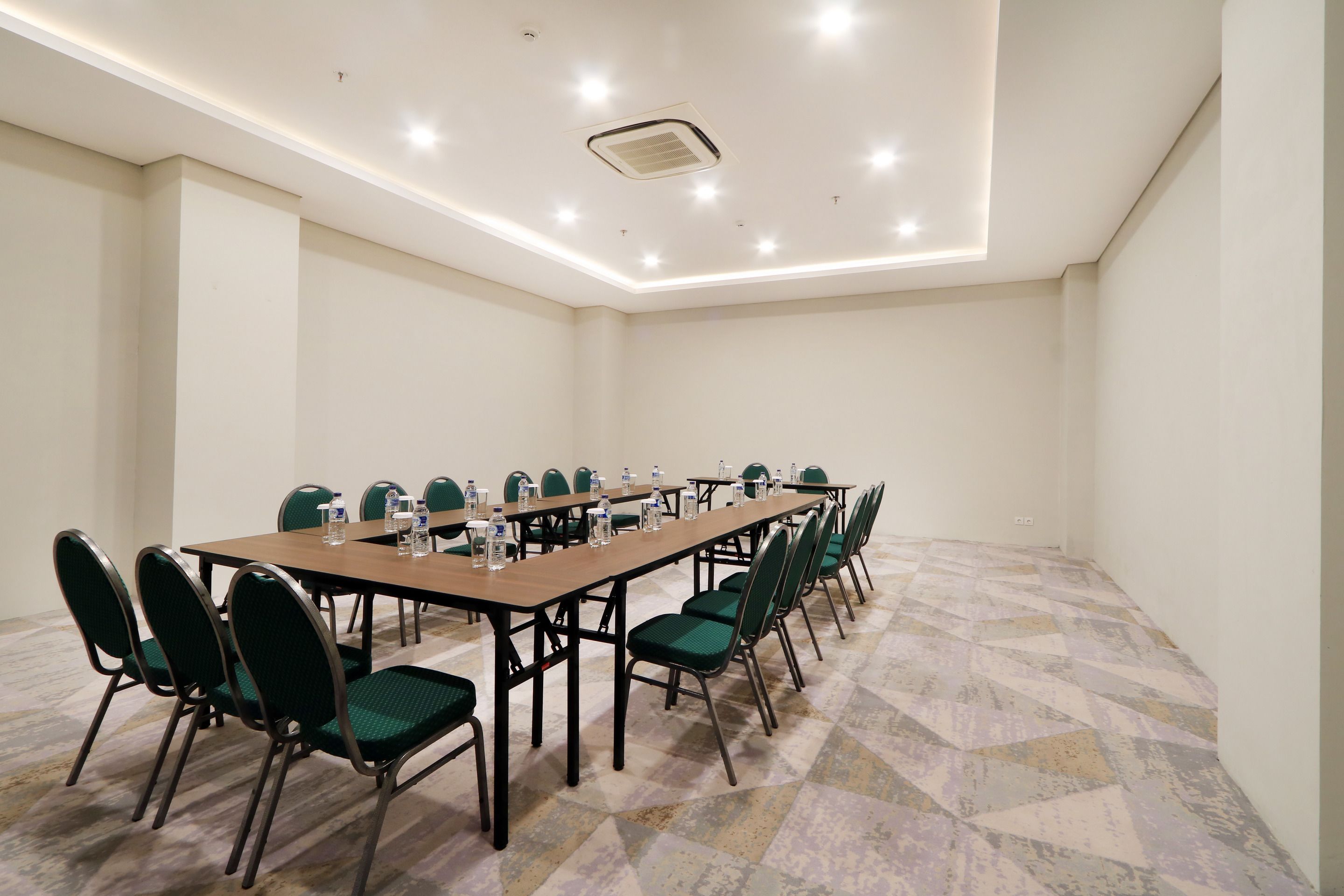 A conference room with a long table, green chairs, and water bottles.