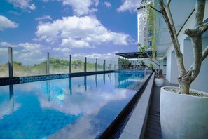 An infinity pool with a clear view of the sky and greenery in the background. - Hotel FortunaGrande Jember (Jember)