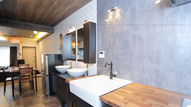 A modern kitchen with a wooden countertop, two white sinks, and a large mirror above the sink. - Villa Ikebukuro Altair (Tokyo)