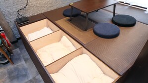 A compact room with a bed, a small table, and two stools. - Villa Ikebukuro Altair (Tokyo)