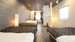 A hotel room with three beds, wooden ceiling, and a hallway leading to a bathroom. - Villa Ikebukuro Altair (Tokyo)