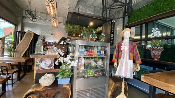 A café interior with a wooden counter, a refrigerated display case, and a mannequin dressed in traditional attire. - Buasri by Ohm (Patong)