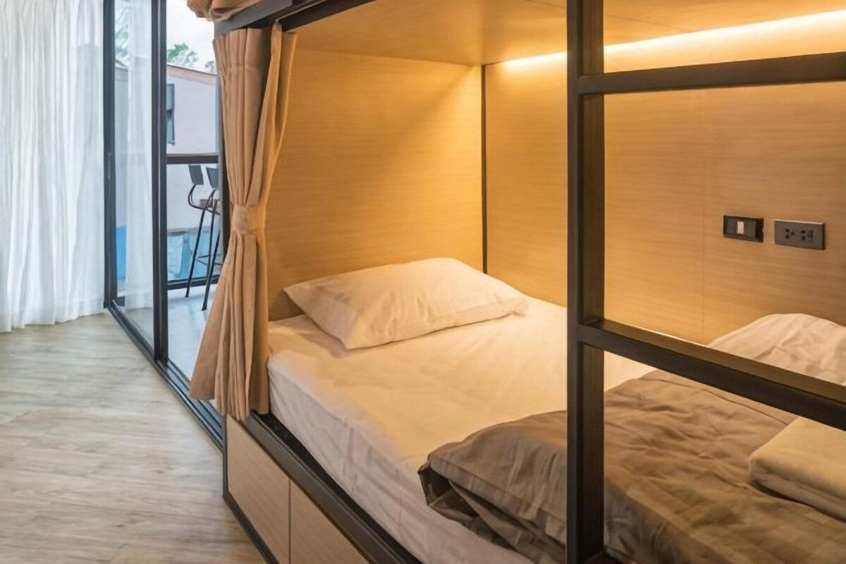 A bunk bed with a wooden frame, a small table, and a chair in the background.