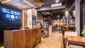 A modern interior with a reception desk, wooden accents, and a visible 'Sleep Box' sign. - Sleep Box Patong - Hostel (Patong)