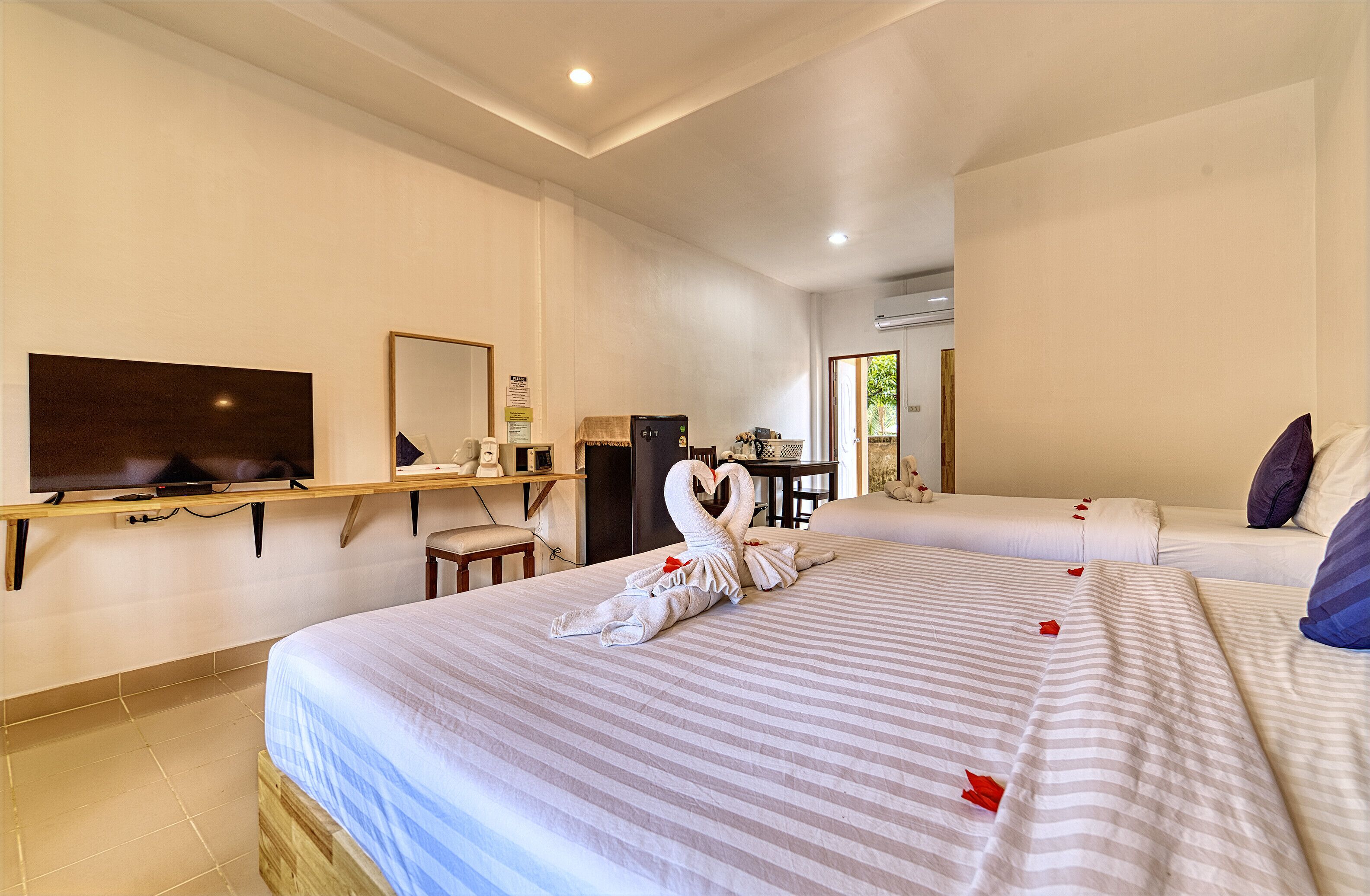 Una habitación de hotel con dos camas, televisión, escritorio y espejo.