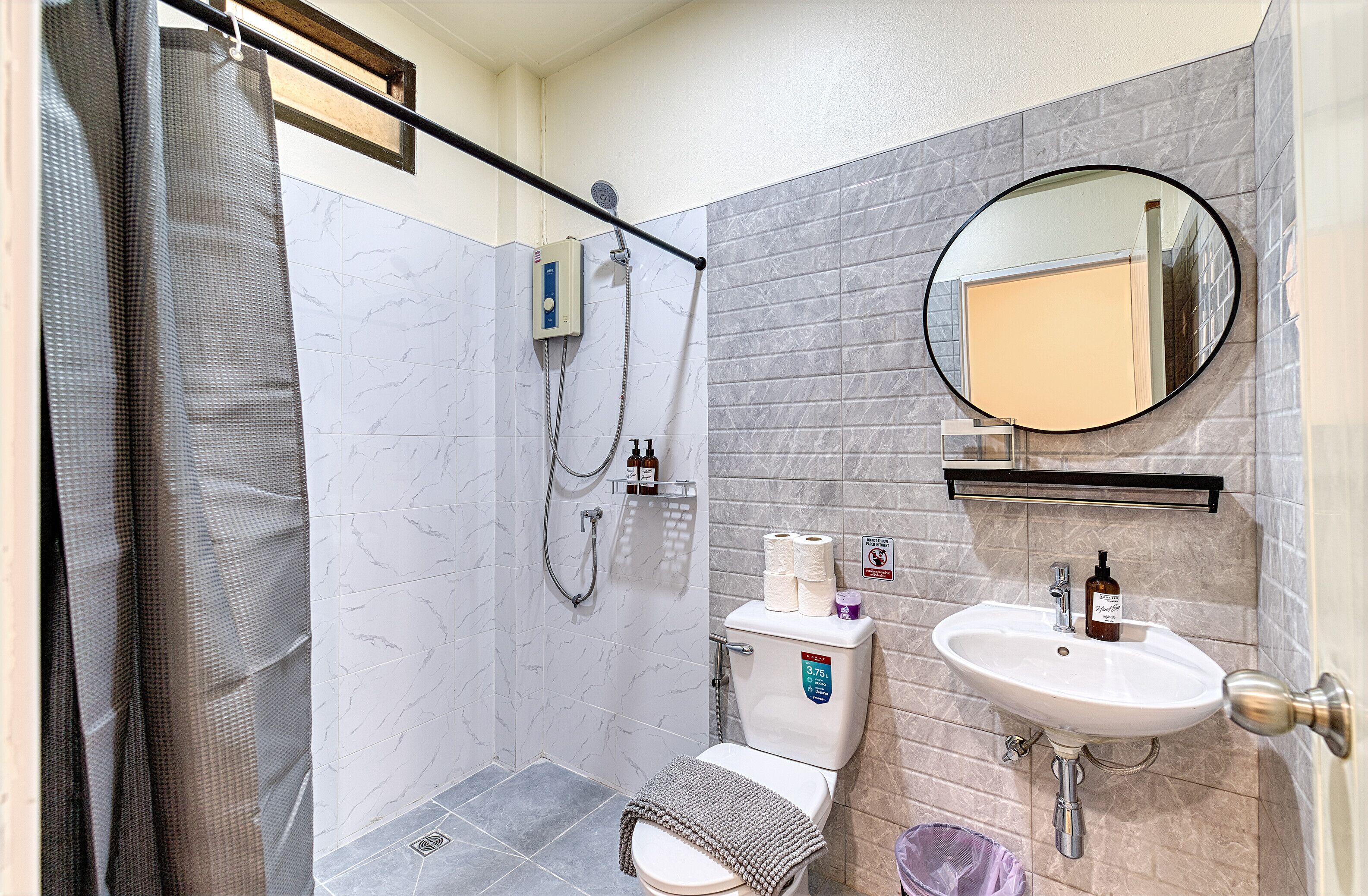 Une salle de bain équipée d’une douche, de toilettes, d’un lavabo et d’un miroir.