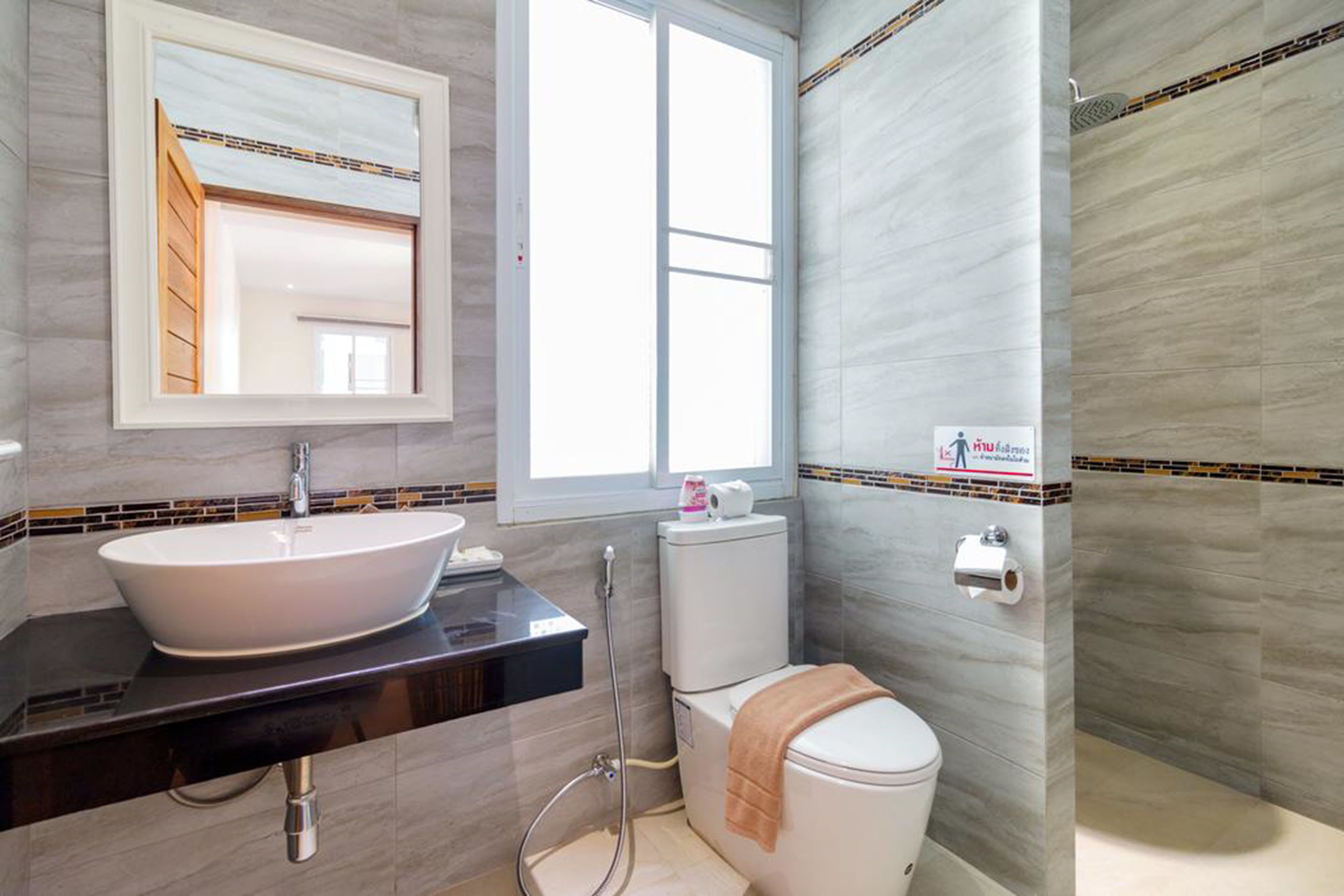 A bathroom with a white sink, a mirror, a toilet, and a shower area.