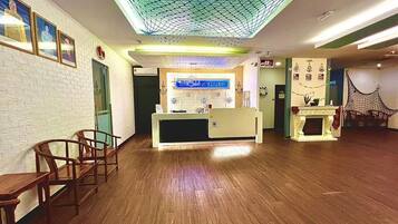 A reception area with a wooden floor, a reception desk, and a wall-mounted sign.